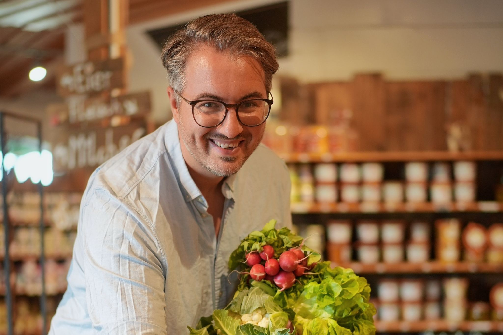 Nobilis kocht auf – Frisches Gemüse und Kochszene Nobilis kocht auf – Mann mit frischem Gemüse in einer Küche oder Feinkostladen