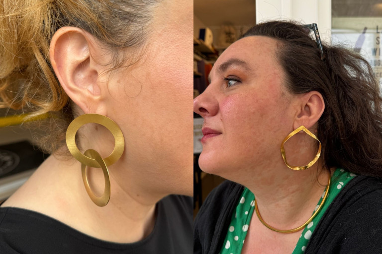 OhMyGoddess Statement-Schmuck: Goldene Ohrringe und Halskette an Frau OhMyGoddess goldene Statement-Ohrringe und Halskette an einer Frau getragen
