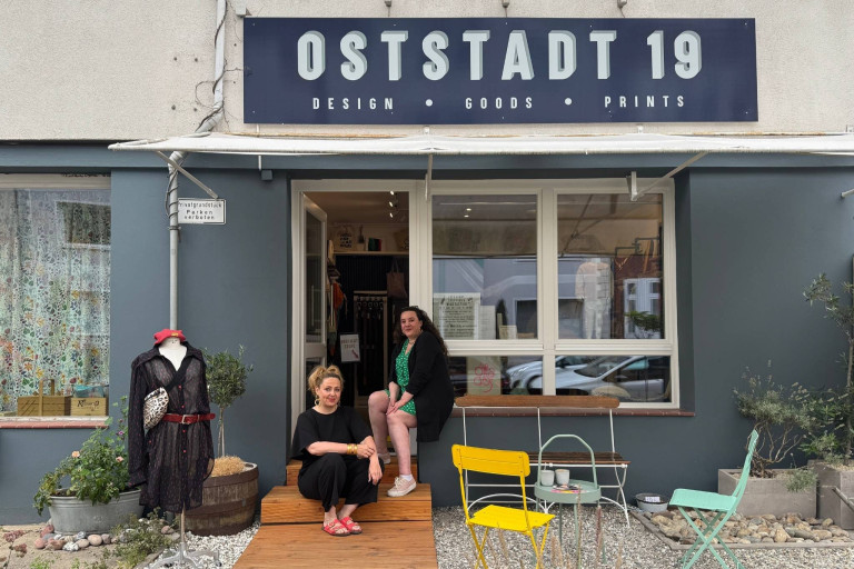 OSTSTADT 19 Design Goods Prints – Ladenfront mit Sitzbereich und Schaufensterpuppe Eingang von OSTSTADT 19 Design Goods Prints mit zwei Frauen und Schaufensterpuppe vor dem Laden