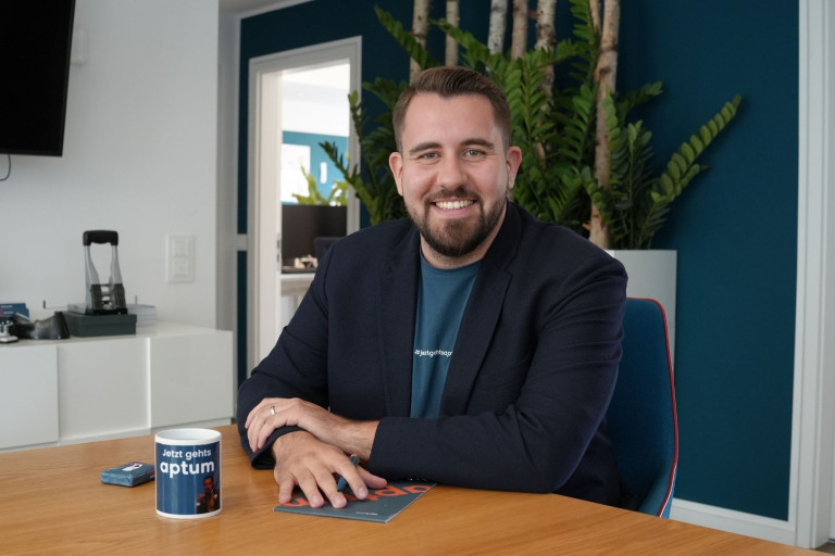 Dominik Talhof im modernen Büro mit aptum-Tasse am Tisch