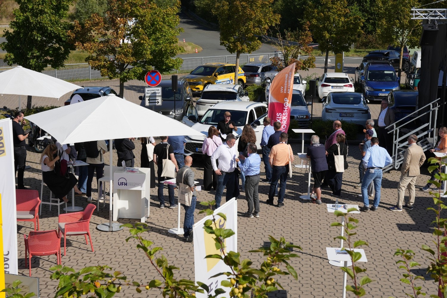 Forum Mobility Work: Teilnehmer auf dem Außengelände mit Autos und Workshop Außenbereich eines Forums zum Thema Mobilität mit Teilnehmern, Autos und Workshop-Bereich