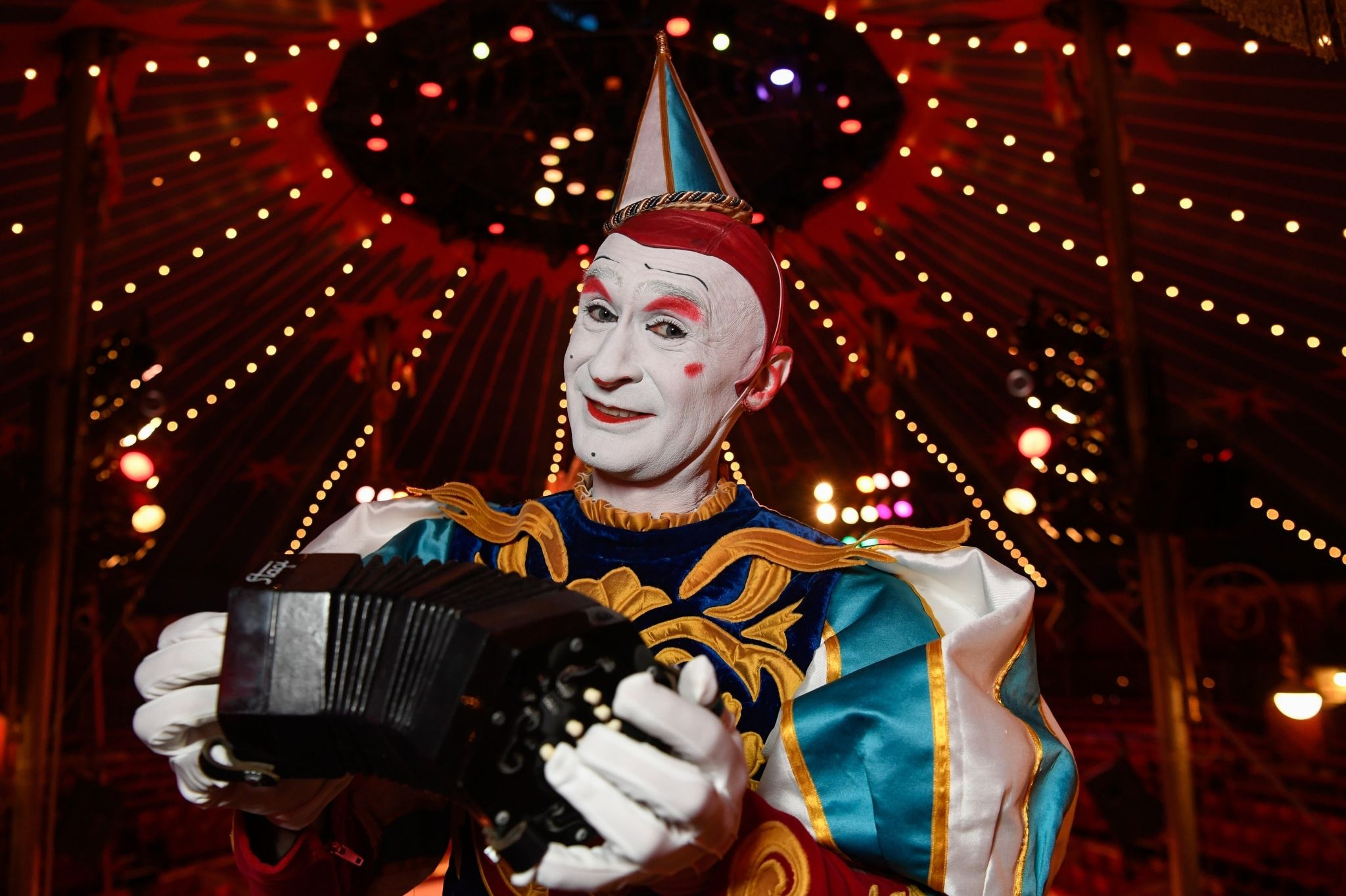 Clown im Circus Roncalli spielt Akkordeon unter der Zirkuskuppel Clown im Circus Roncalli mit Akkordeon unter der Zirkuskuppel