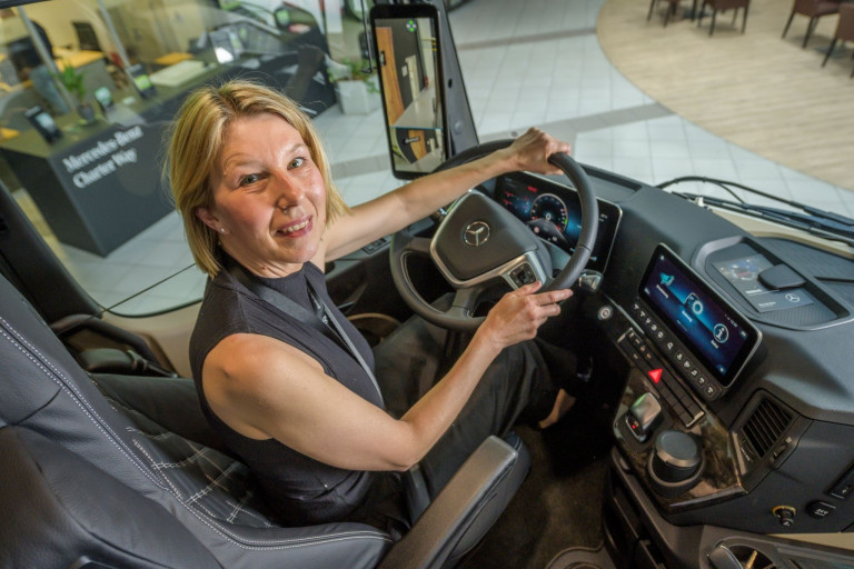 Fuhrparkmanagerin im Cockpit eines Mercedes-Lkw Fuhrparkmanagerin sitzt am Steuer eines modernen Lkw mit Mercedes-Logo im Innenraum