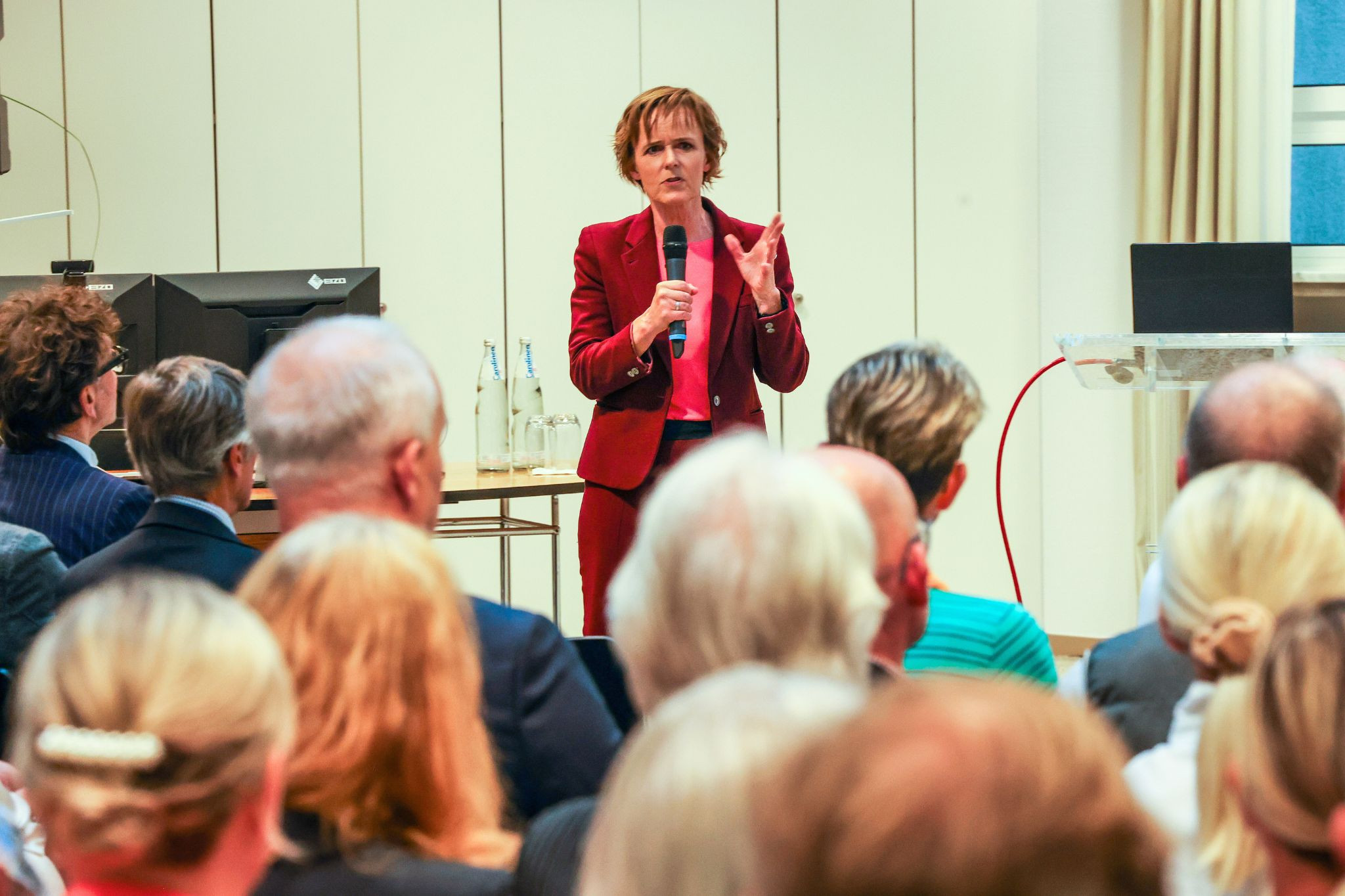 Vortrag in Warburg – Rednerin spricht vor Publikum Vortrag in Warburg vor Publikum, Rednerin mit Mikrofon