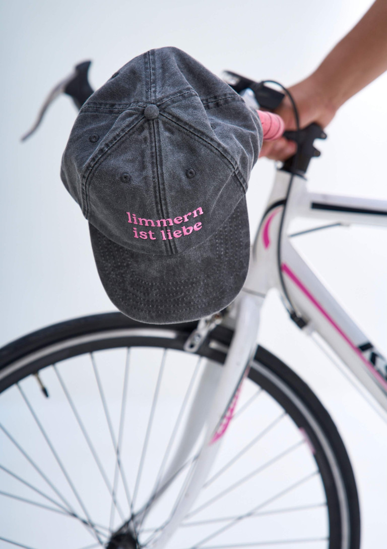 Graue Cap mit pinker Aufschrift 'limmern ist liebe' auf Fahrradlenker