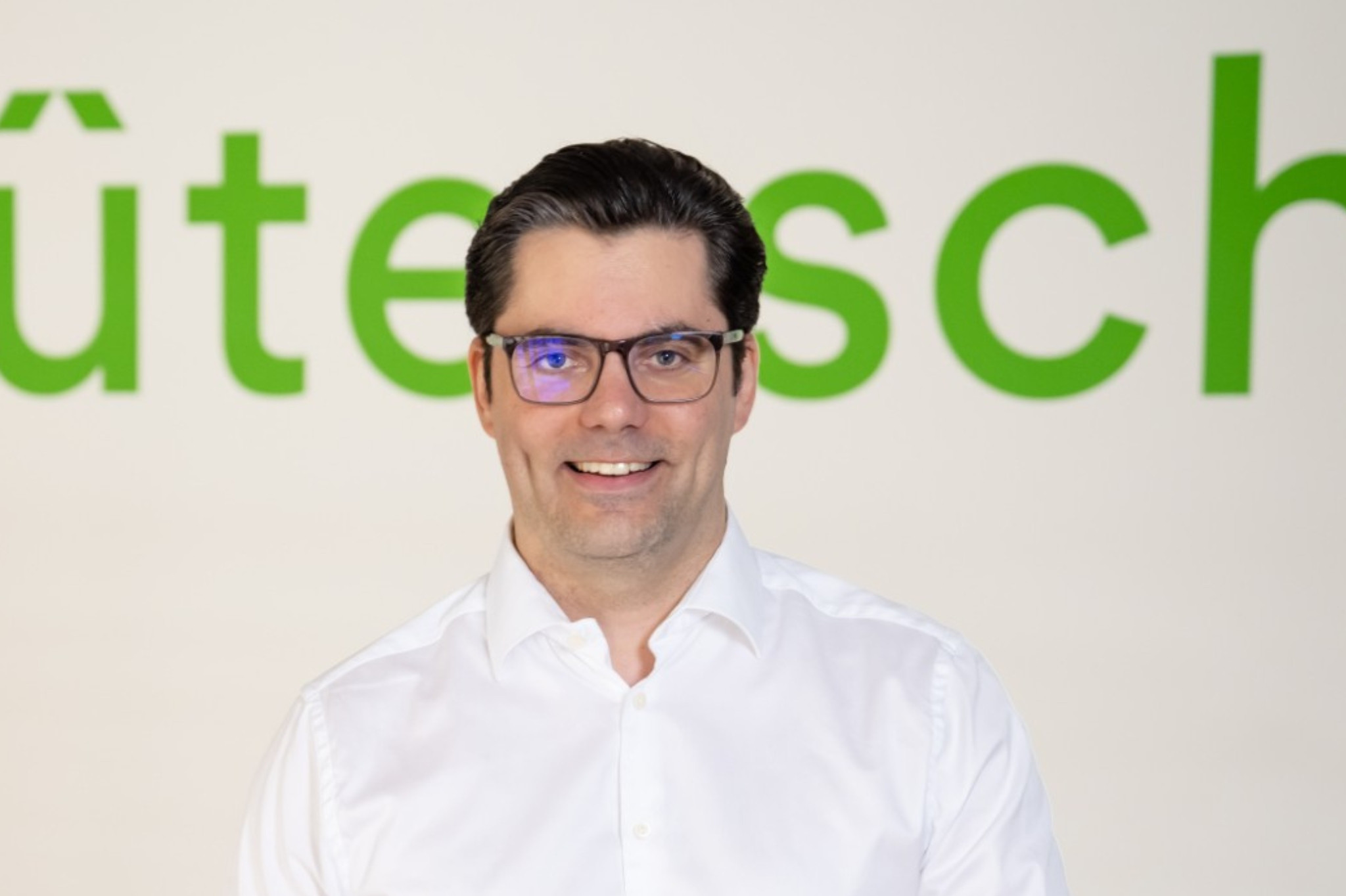 Marco im weißen Hemd vor grünem Schriftzug