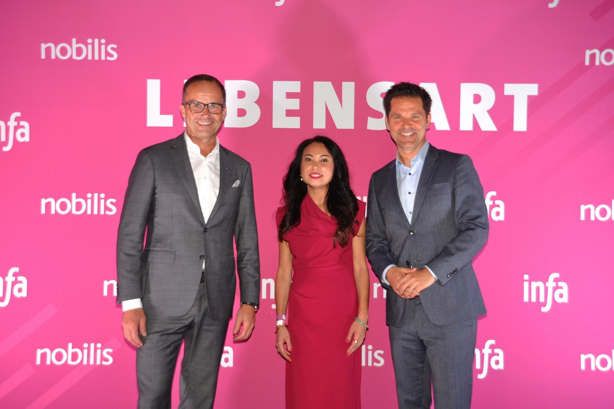 Drei Personen auf der infa Messe vor pinkem Hintergrund mit dem Schriftzug 'Lebensart'