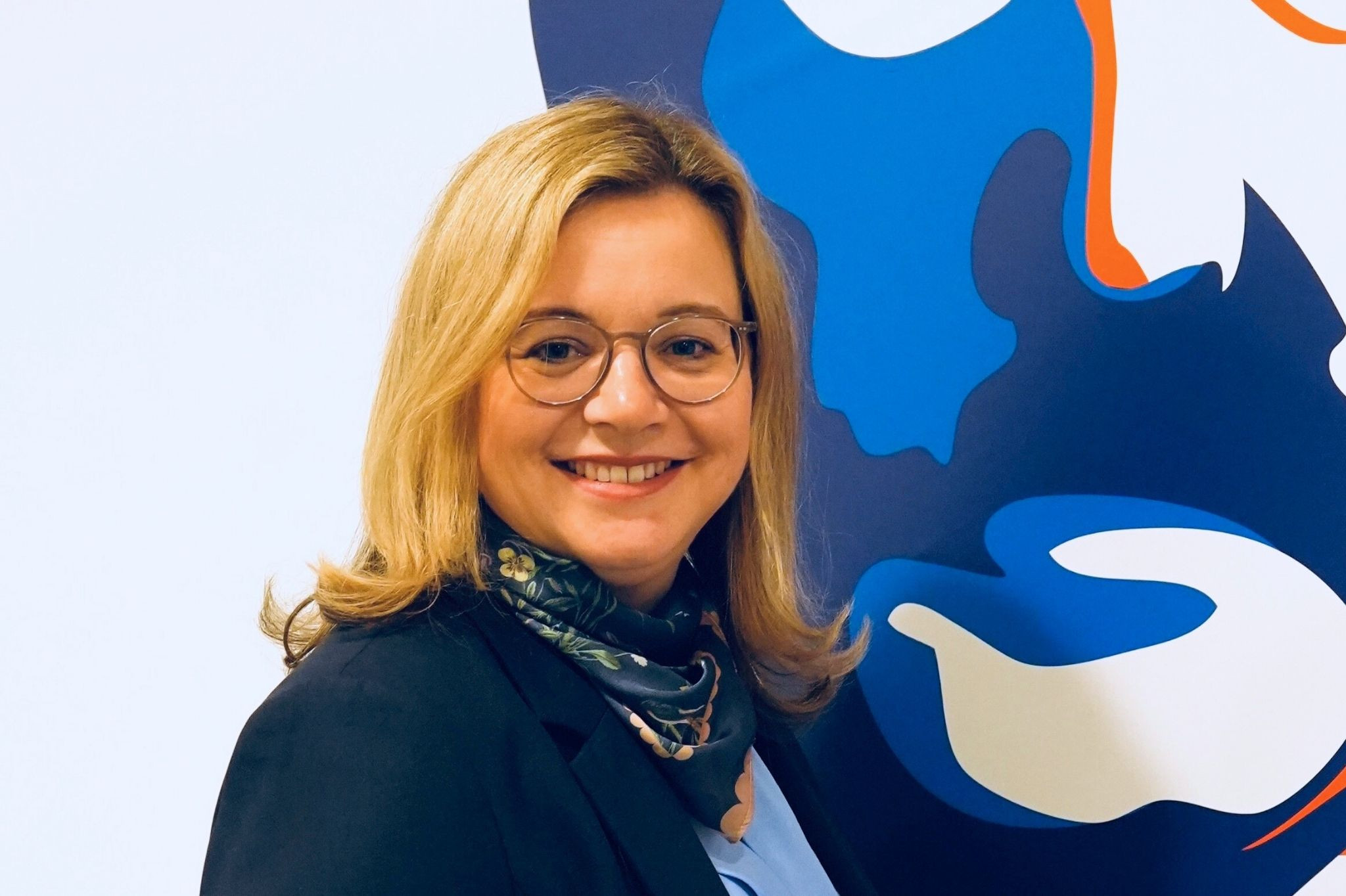 Anne Mahler vor modernem, farbigem Hintergrund