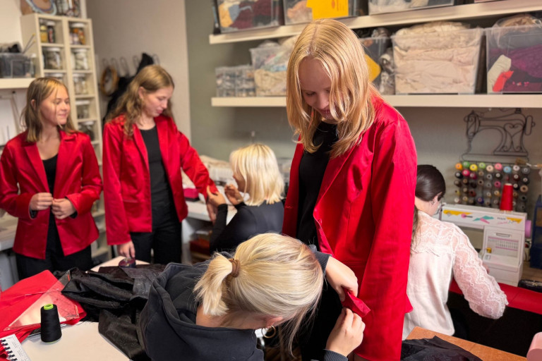 Mädchenchor probiert rote Blazer an und wird beim Anpassen der Kleidung unterstützt