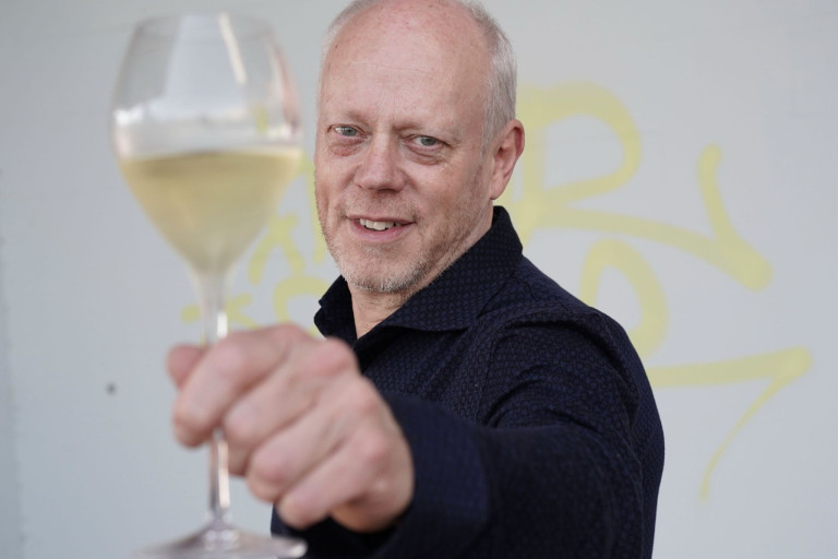 Person hält ein Glas Weißwein von Zebrawein in die Kamera