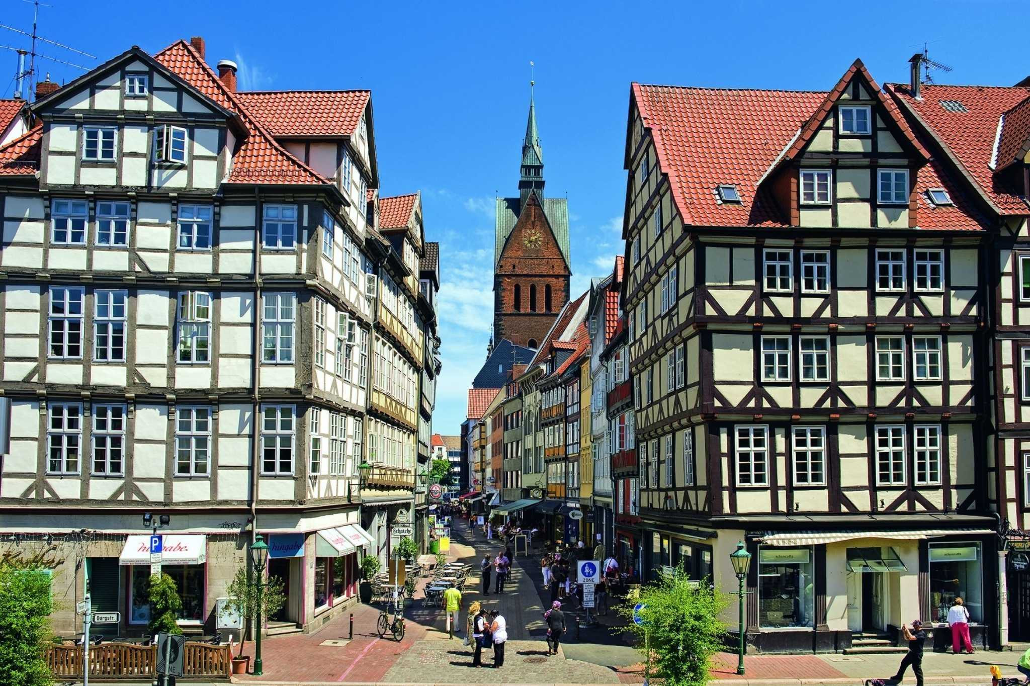 Fachwerkhäuser und das Mantelhaus Kaiser in einer historischen Altstadt mit Kirchturm im Hintergrund