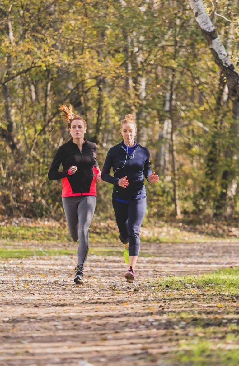 Zwei Frauen joggen im Park in Sportkleidung von Mantelhaus Kaiser