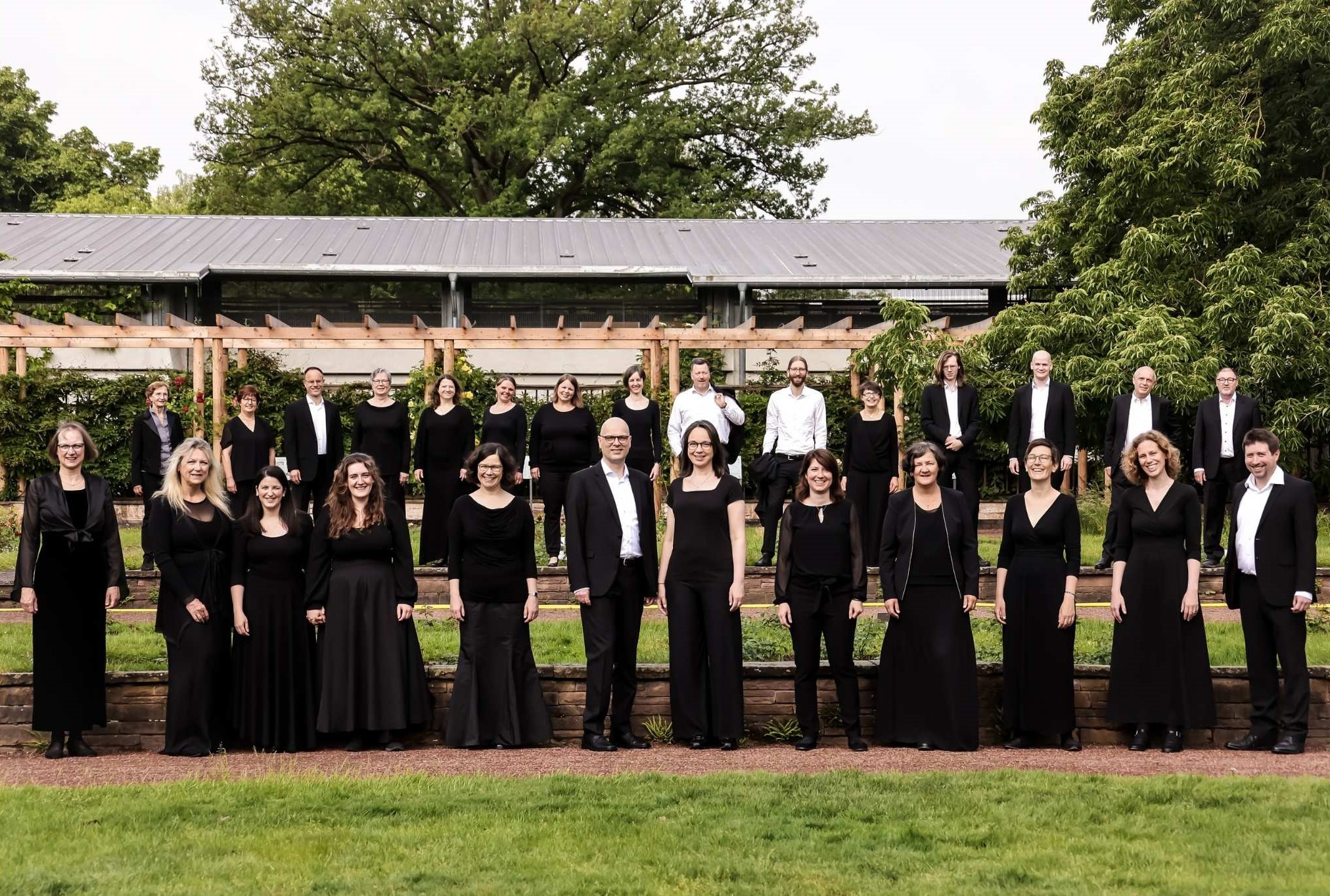 Gruppenfoto vor dem Mantelhaus Kaiser, mehrere Personen in schwarzer Kleidung im Freien