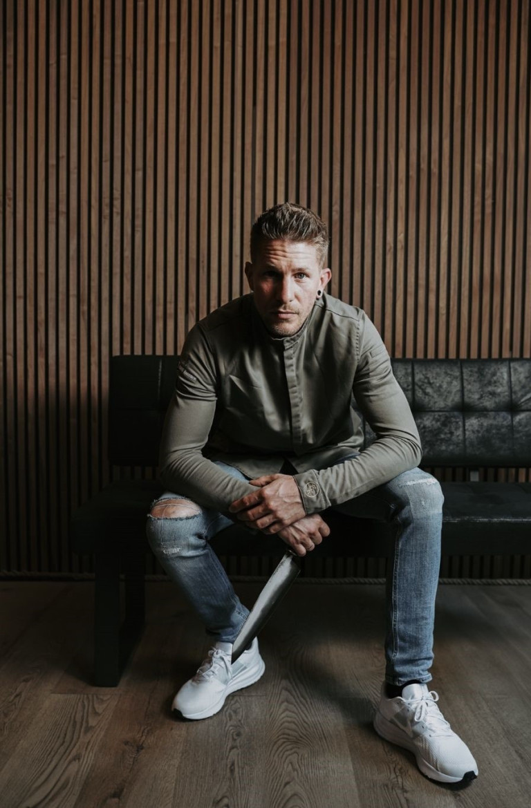 Mann sitzt im Mantelhaus Kaiser auf einer Bank, moderne Einrichtung Mann in moderner Einrichtung mit Jeans und Hemd im Mantelhaus Kaiser