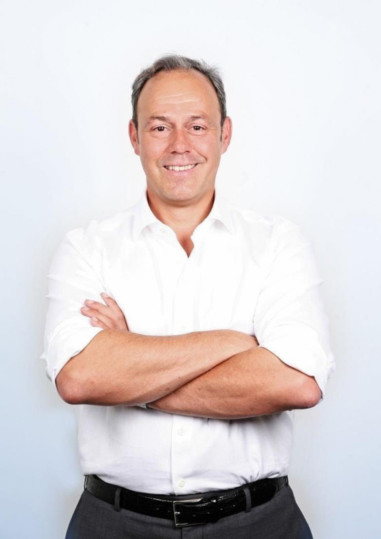 Mitarbeiter von Mantelhaus Kaiser mit verschränkten Armen in weißem Hemd