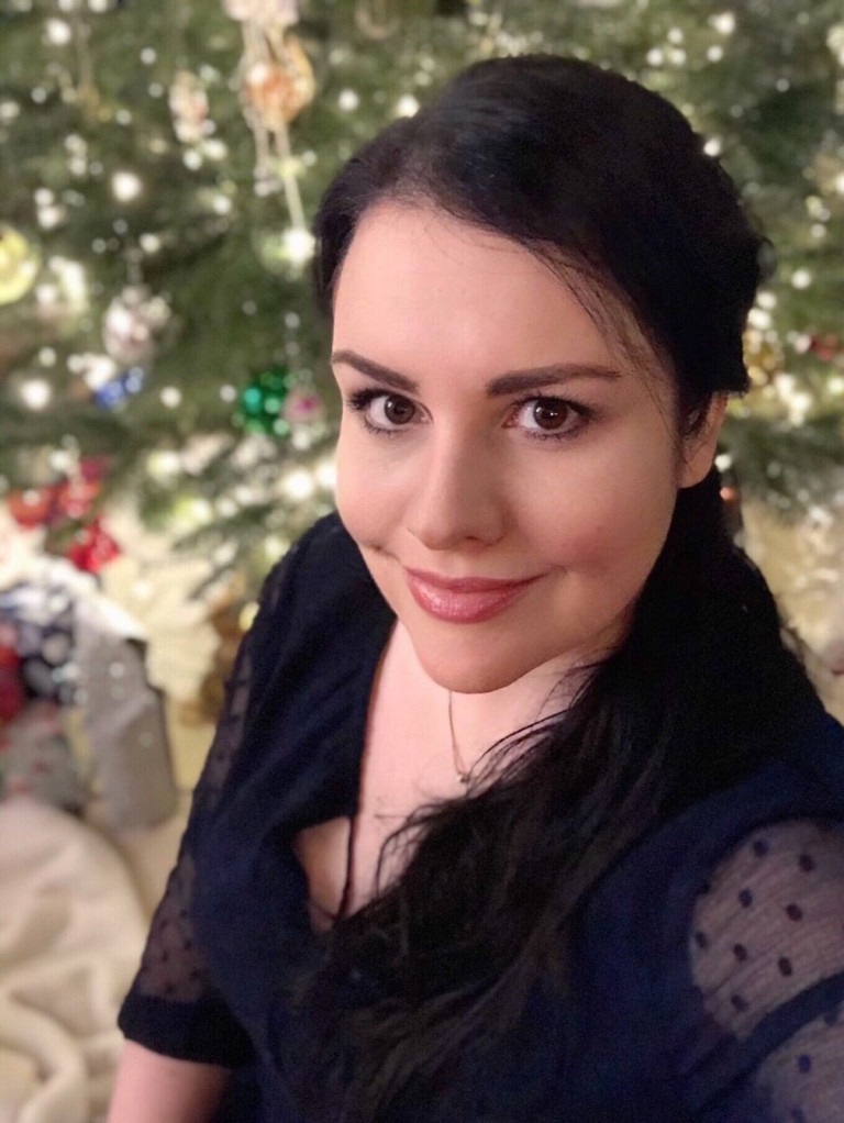 Frau im dunklen Kleid vor einem festlich geschmückten Weihnachtsbaum im Mantelhaus Kaiser