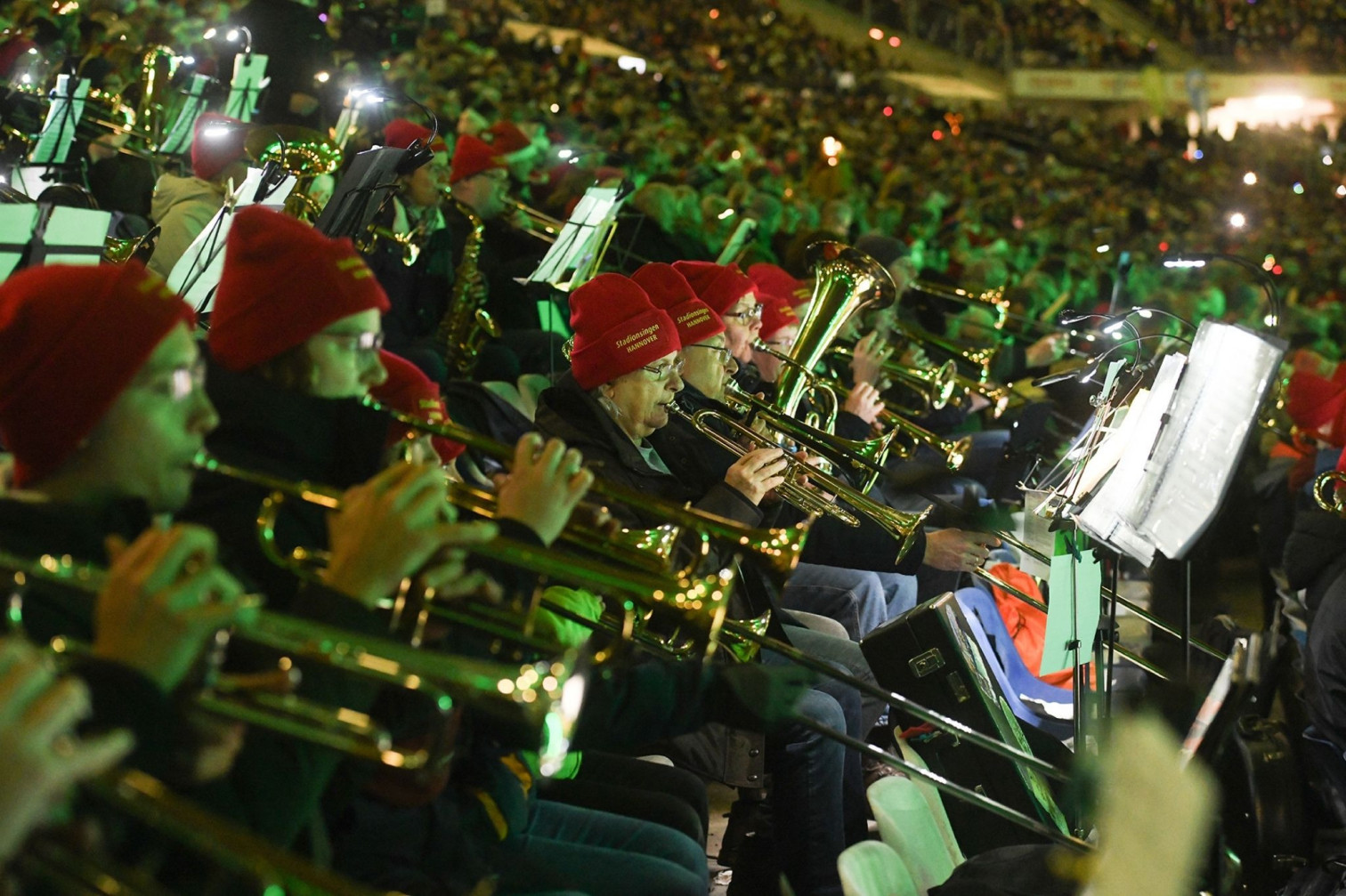 Blasorchester mit roten Mützen beim Stadionsingen in einem vollbesetzten Stadion