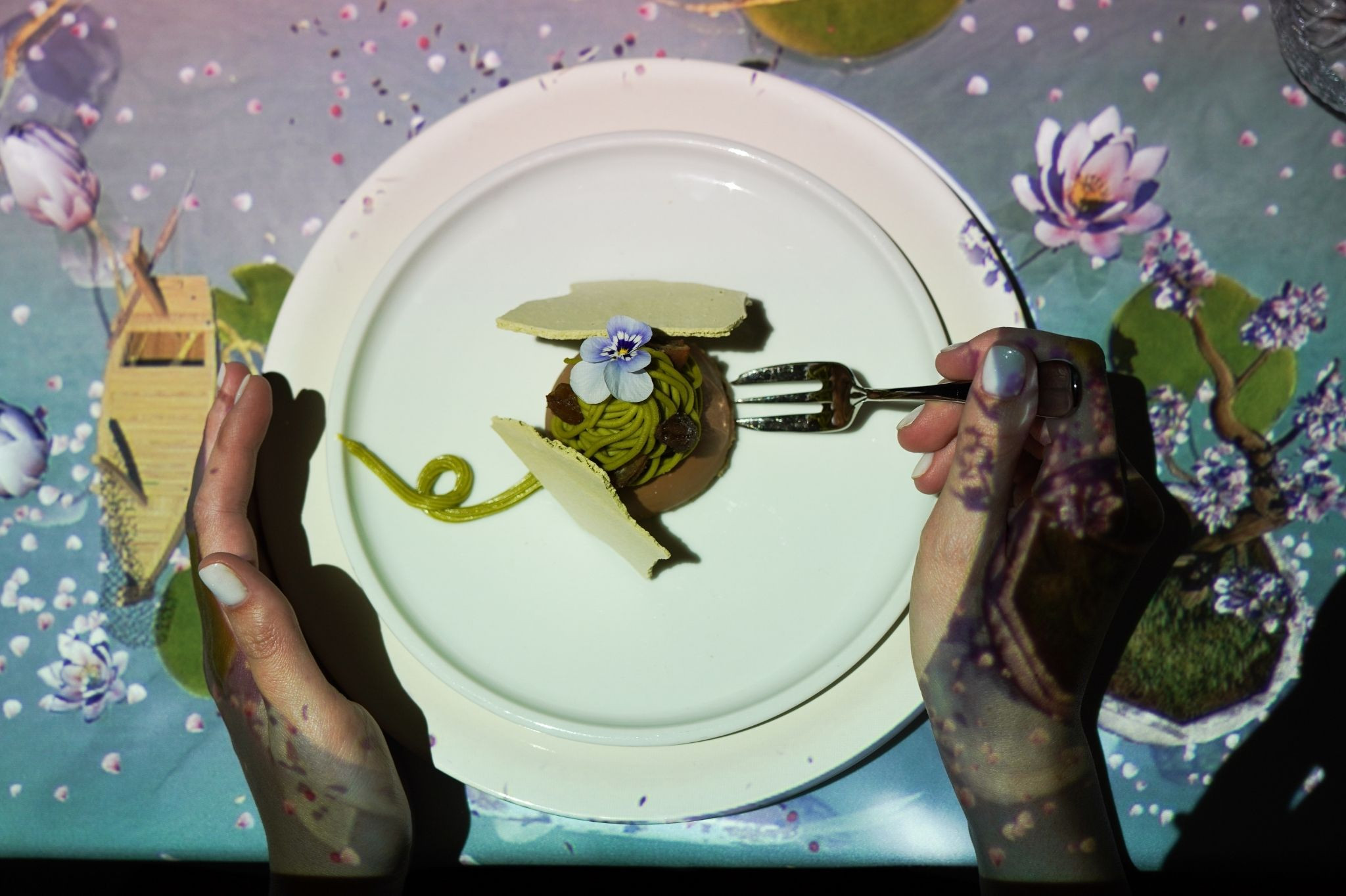 Le Petit Chef Dessert auf weißem Teller mit essbarer Blume und kreativer Präsentation