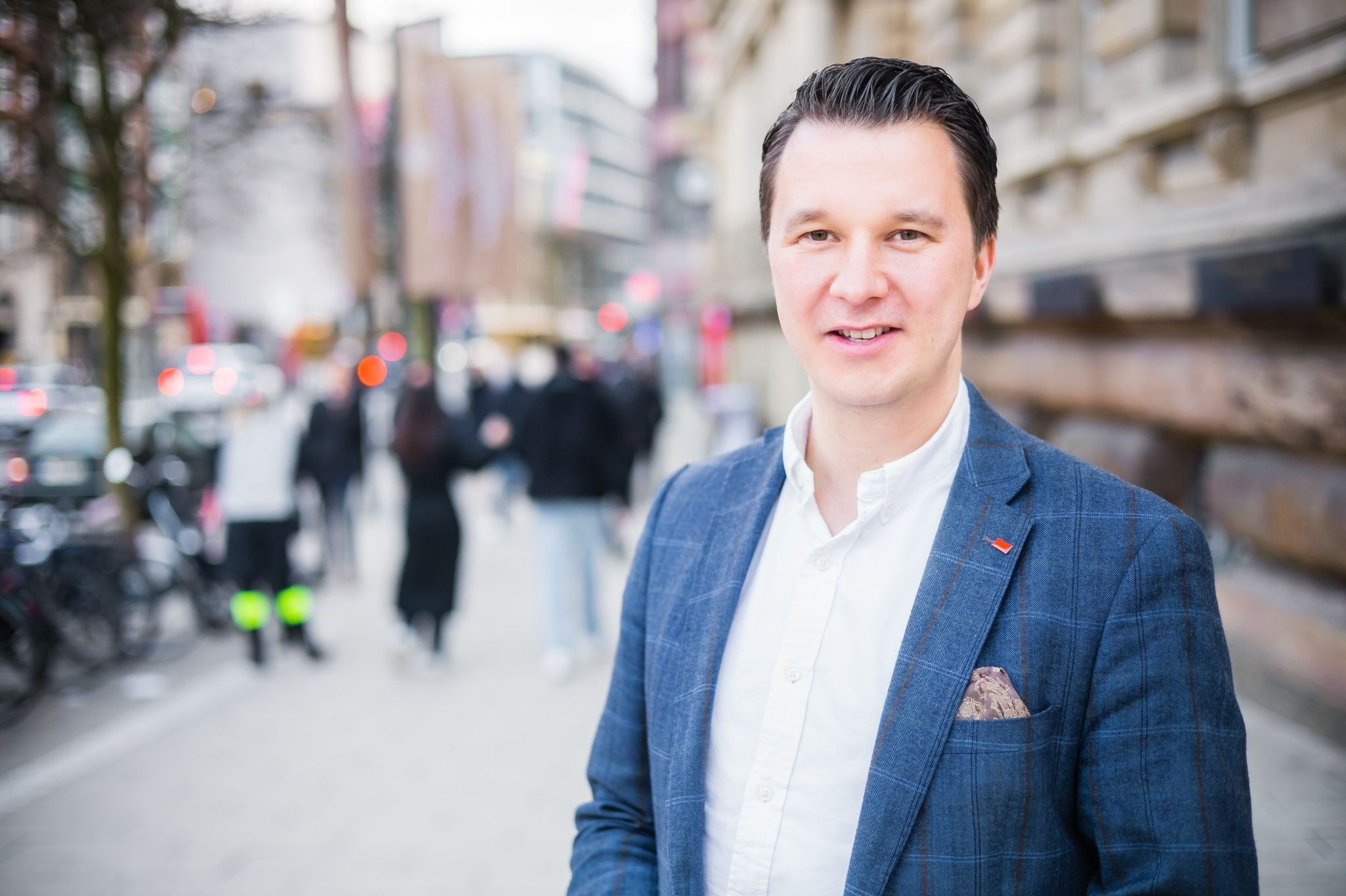 Thomas Hoppe im blauen Sakko auf einer belebten Straße in der Stadt
