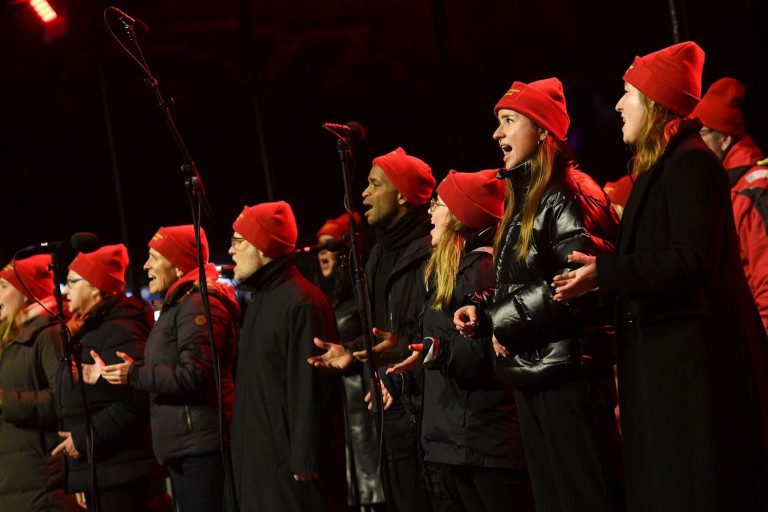 Chor singt auf der Bühne beim Weihnachtszauber-Event, festliche Stimmung mit roten Mützen