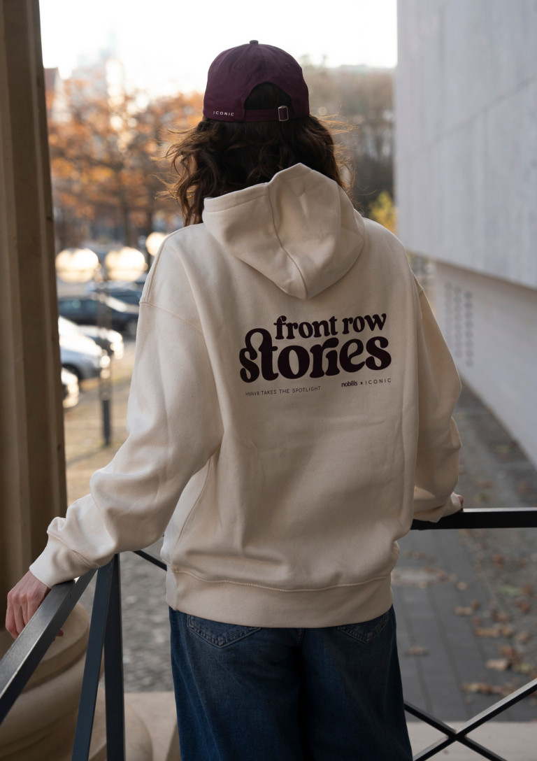 Person mit cremefarbenem Hoodie mit Aufdruck 'front row stories', nobilis x ICONIC Kollektion, draußen im Herbst
