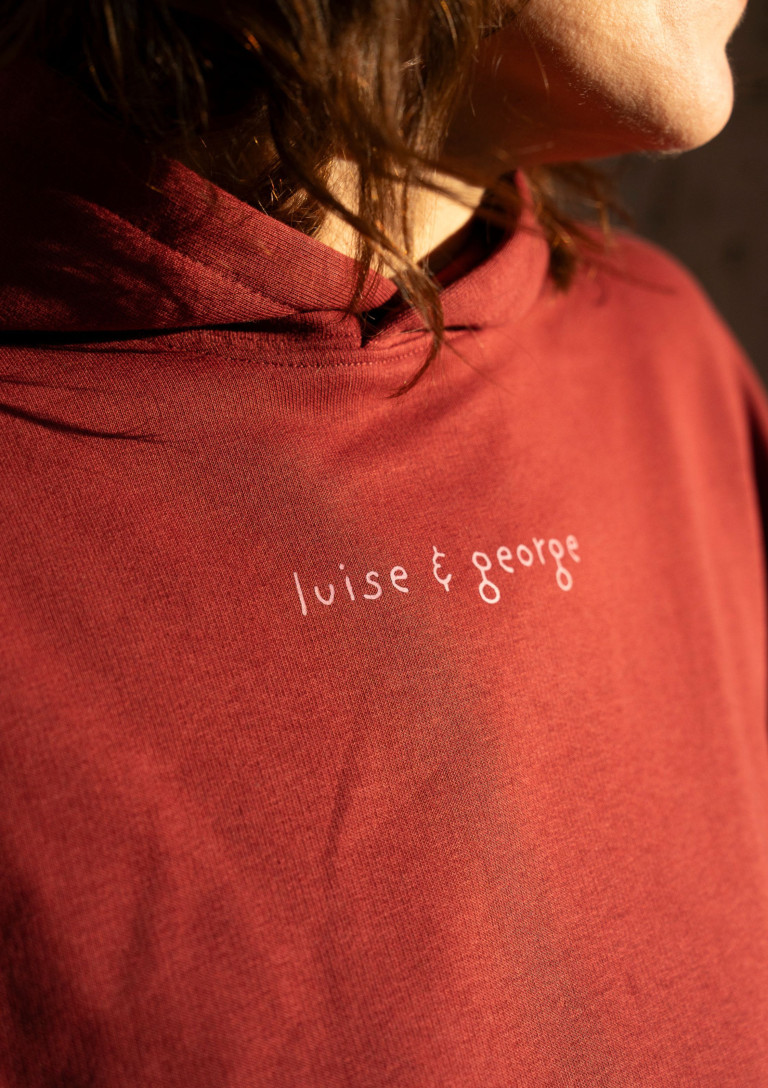 Nahaufnahme eines roten T-Shirts mit dem Aufdruck 'luise & george'