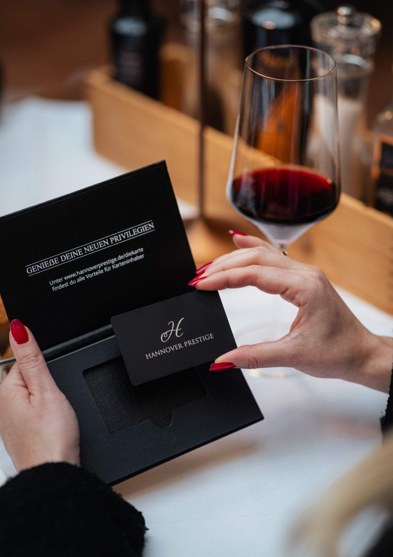 Hannover Prestige Karte – exklusive Vorteile für Karteninhaber Hannover Prestige Karte wird aus edler Verpackung entnommen, daneben ein Glas Rotwein
