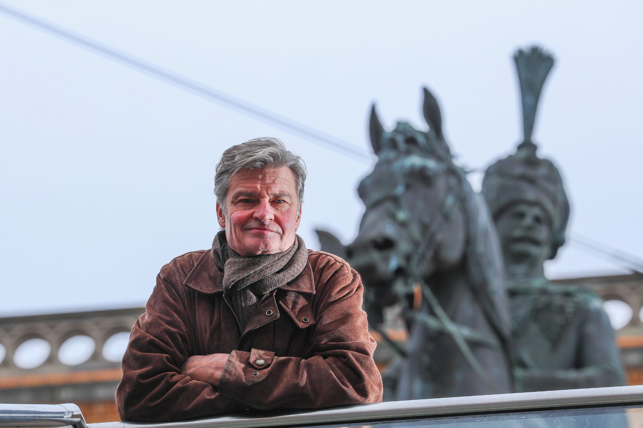 Prinz Heinrich vor einer Pferdeskulptur im Freien