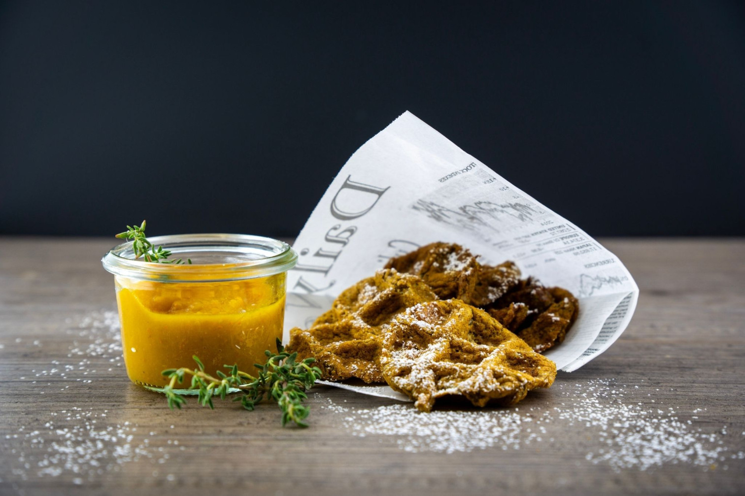 Winterküche: Frische Waffeln mit Puderzucker und Kürbis-Dip auf Zeitungspapier serviert