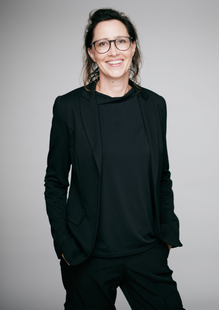 Dr. Eva Jandl-Jörg im schwarzen Blazer vor grauem Hintergrund
