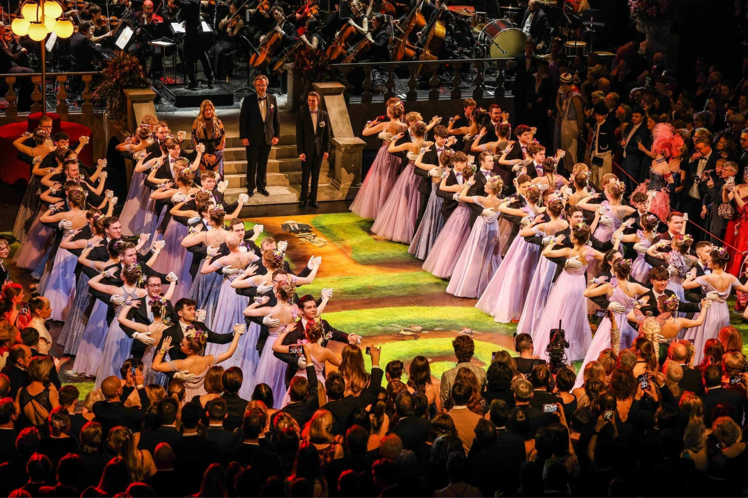 Eröffnungstanz beim Opernball mit Debütantinnen in eleganten Kleidern und Orchester im Hintergrund