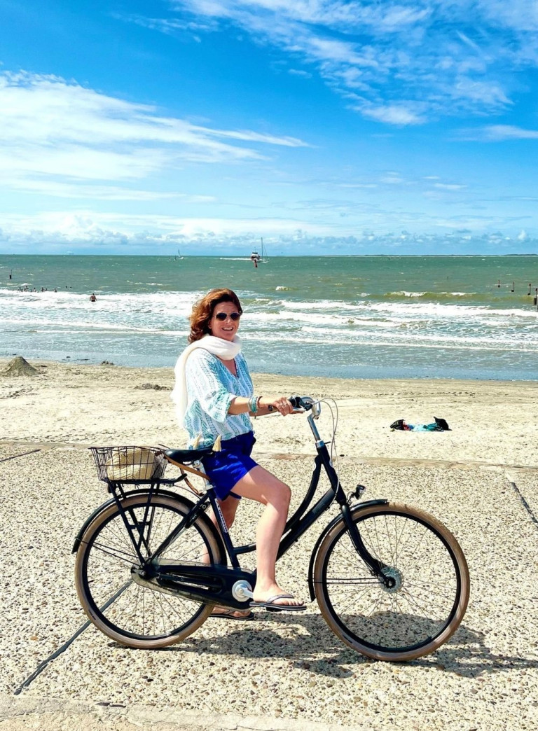 Frau fährt Fahrrad am Strand, sonniges Wetter, Lieblingsreiseziele am Meer