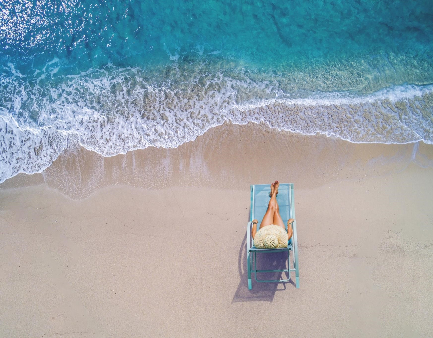 Frau entspannt am Strand auf einem Liegestuhl mit Blick auf das Meer – artikel lieblingsreiseziele