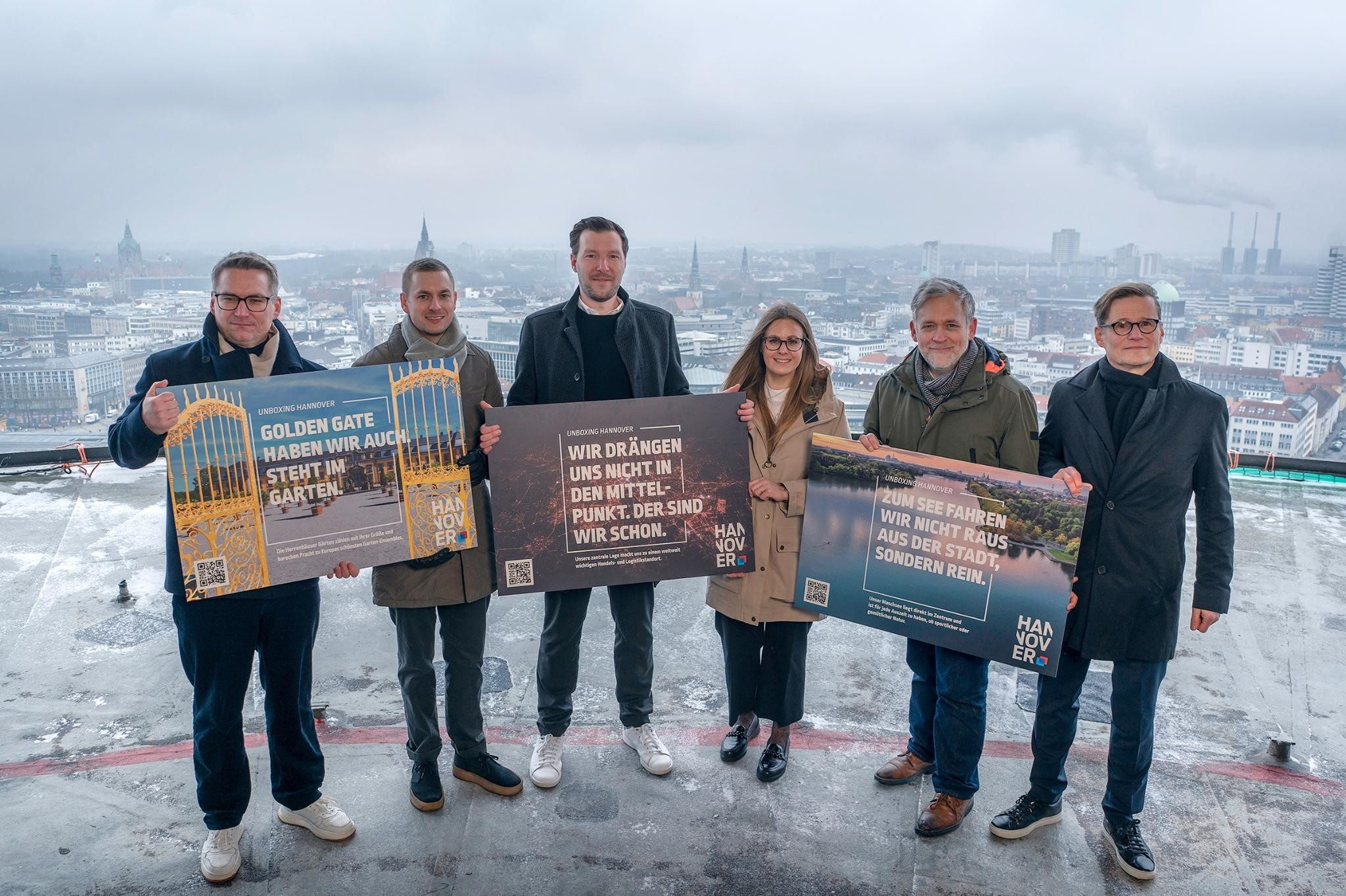 Unboxing Hannover: Gruppe mit Plakaten auf einem Hochhaus mit Blick über Hannover