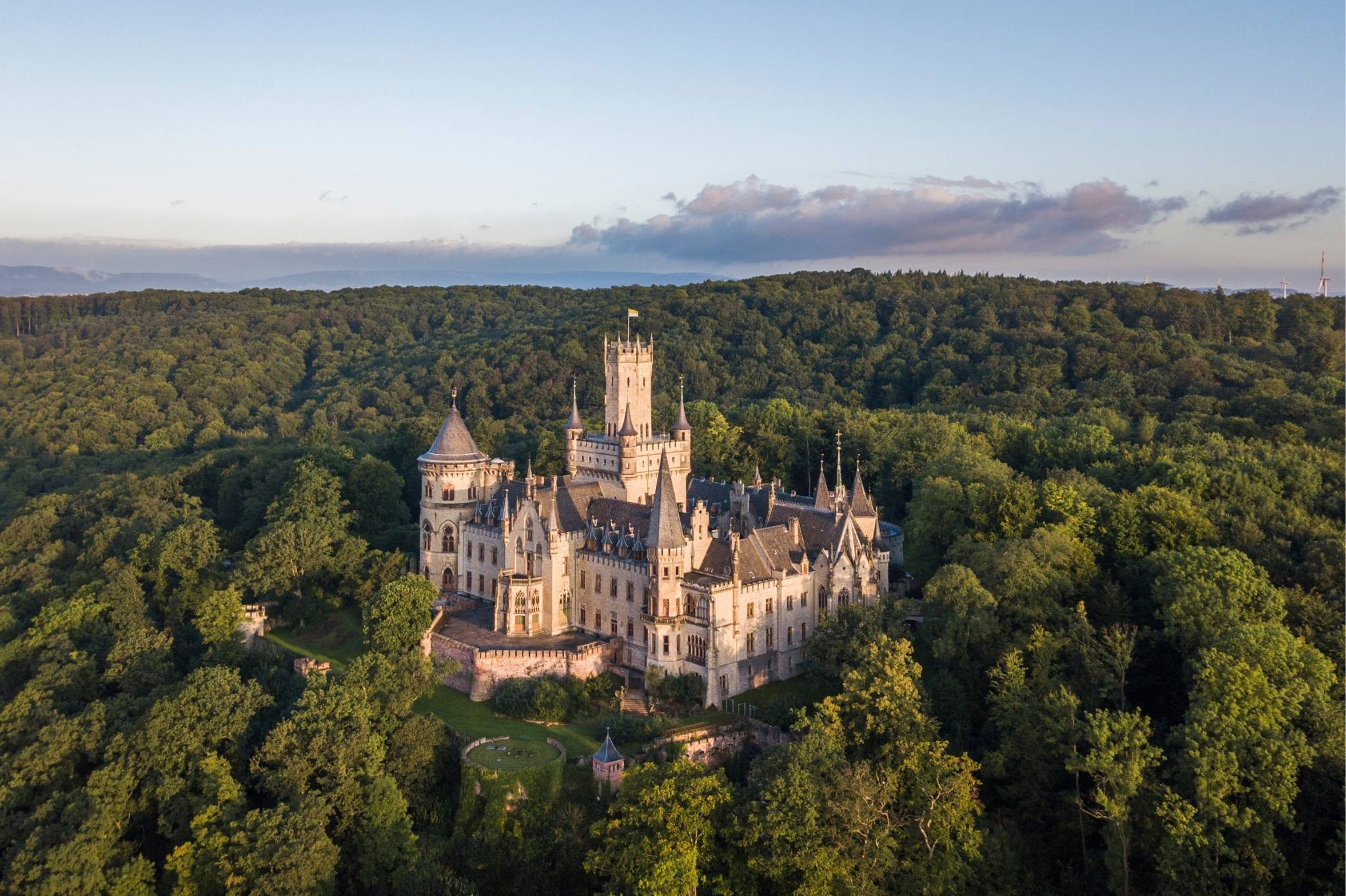 Historische Entdeckungstouren: Luftaufnahme einer imposanten Burg inmitten eines Waldes