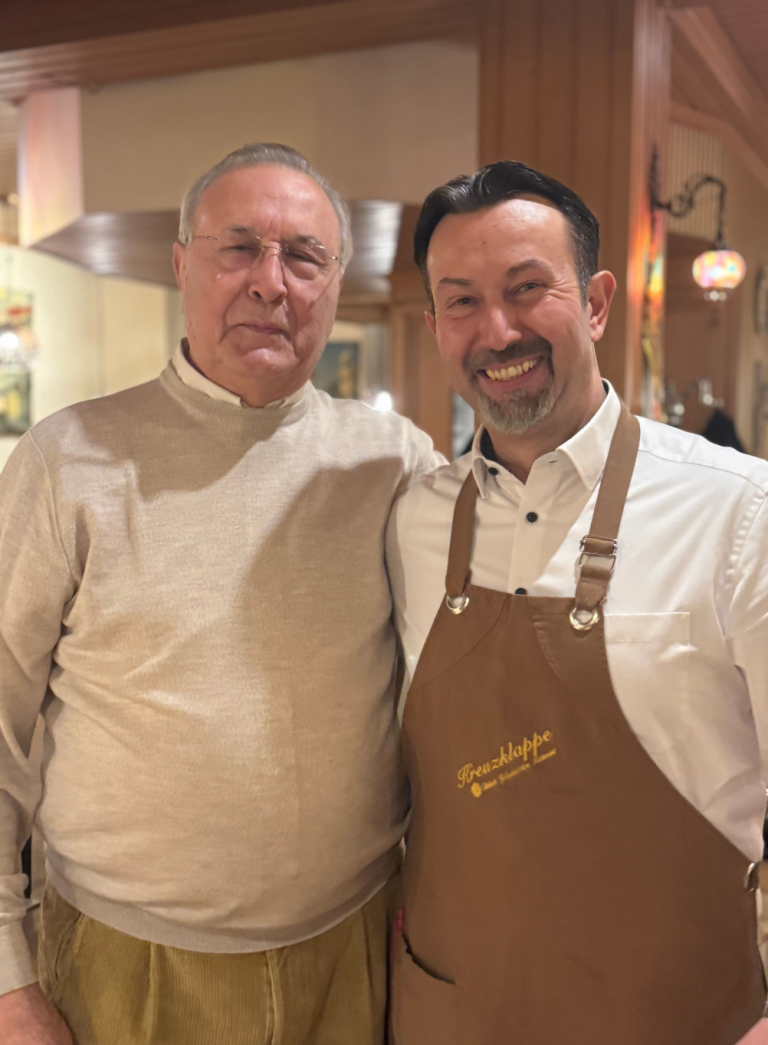 Zwei Personen im Restaurant Kreuzklappe, einer mit Kreuzklappe-Schürze