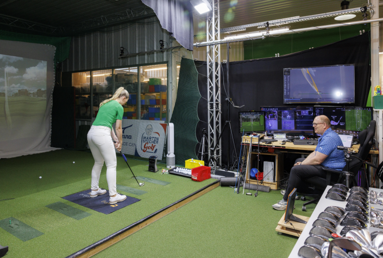 Golf-Fitting in einem modernen Indoor-Golfstudio mit Analyse-Technik und Golfschlägern