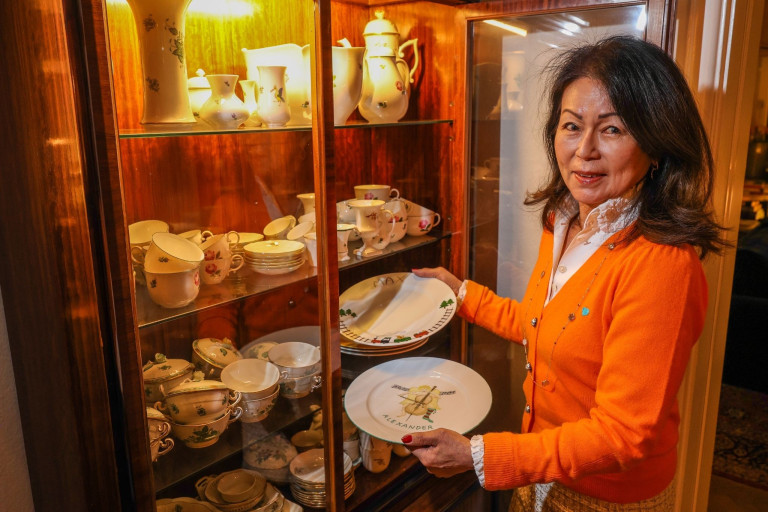 Frau stellt Porzellanteller in eine Vitrine bei Schober Homestory