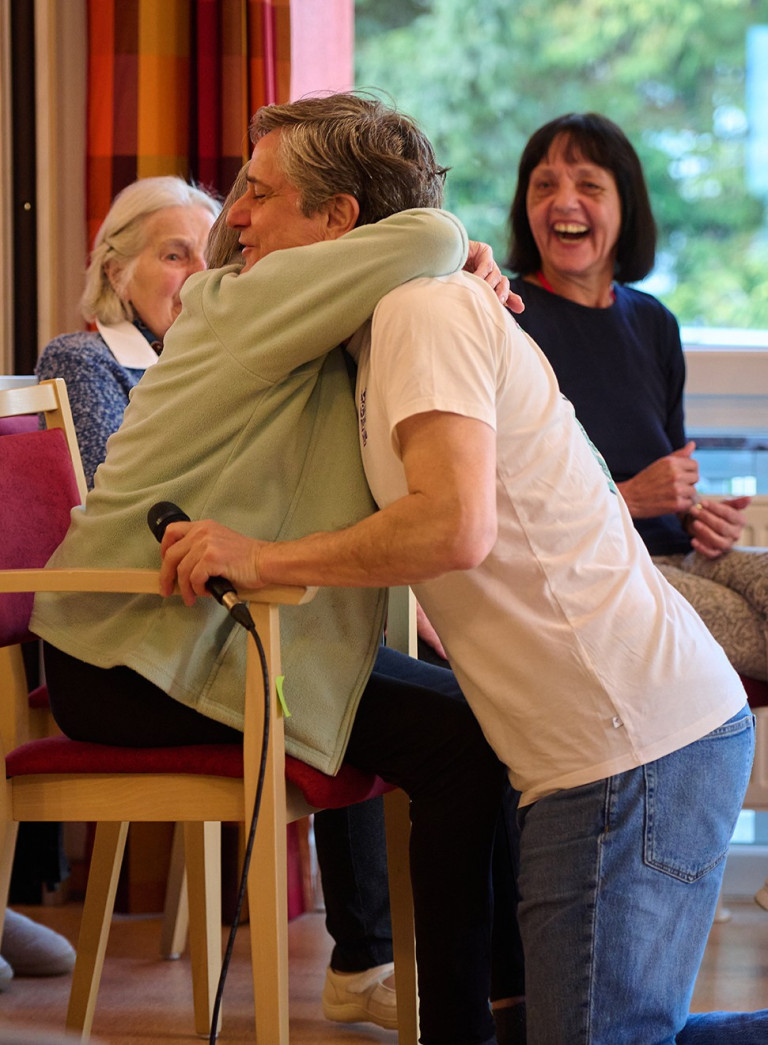 Herzliche Umarmung bei einer Klang und Leben Veranstaltung, Senioren und Betreuer im Austausch