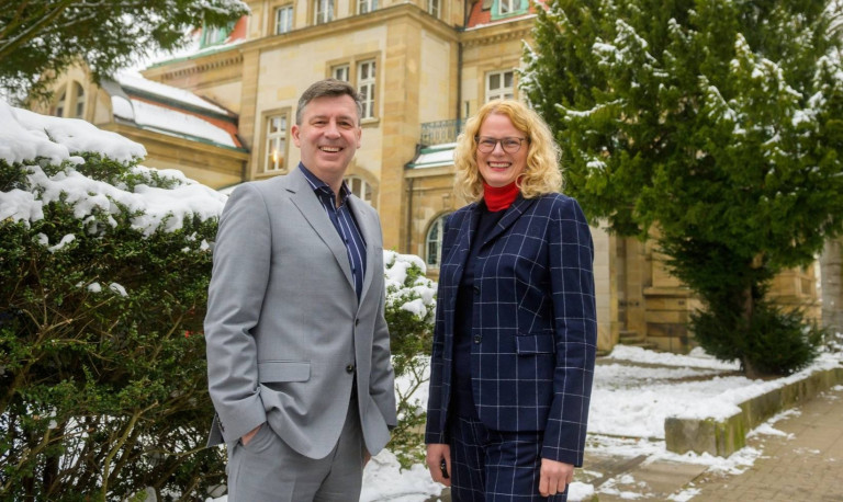 Zwei Personen im Business-Outfit vor dem Industrieclub-Gebäude im Winter