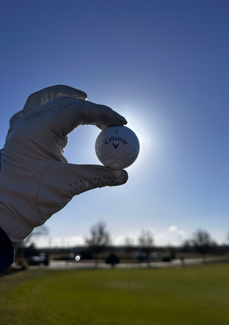 Golfkolumne: Golfball mit Handschuh auf dem Golfplatz bei Sonnenschein Golfkolumne – Golfball in Handschuh-Hand vor blauem Himmel auf dem Golfplatz