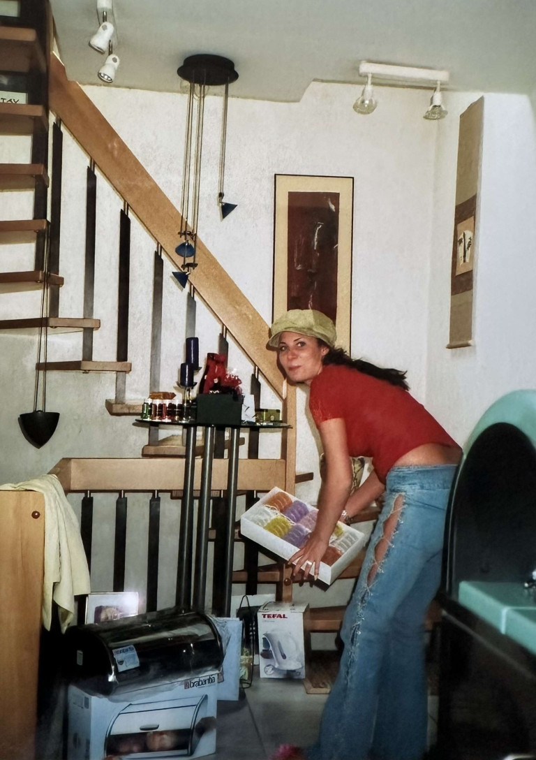 Frau in den 90er Jahren mit zerrissener Jeans und rotem Shirt in einem Wohnzimmer mit typischer 90er-Jahre-Einrichtung