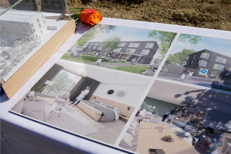 Spatenstich: Visualisierung und Pläne eines Bauprojekts beim offiziellen Baustart Visualisierung und Pläne eines Bauprojekts beim Spatenstich, mit Architekturmodell und Blume auf einem Tisch