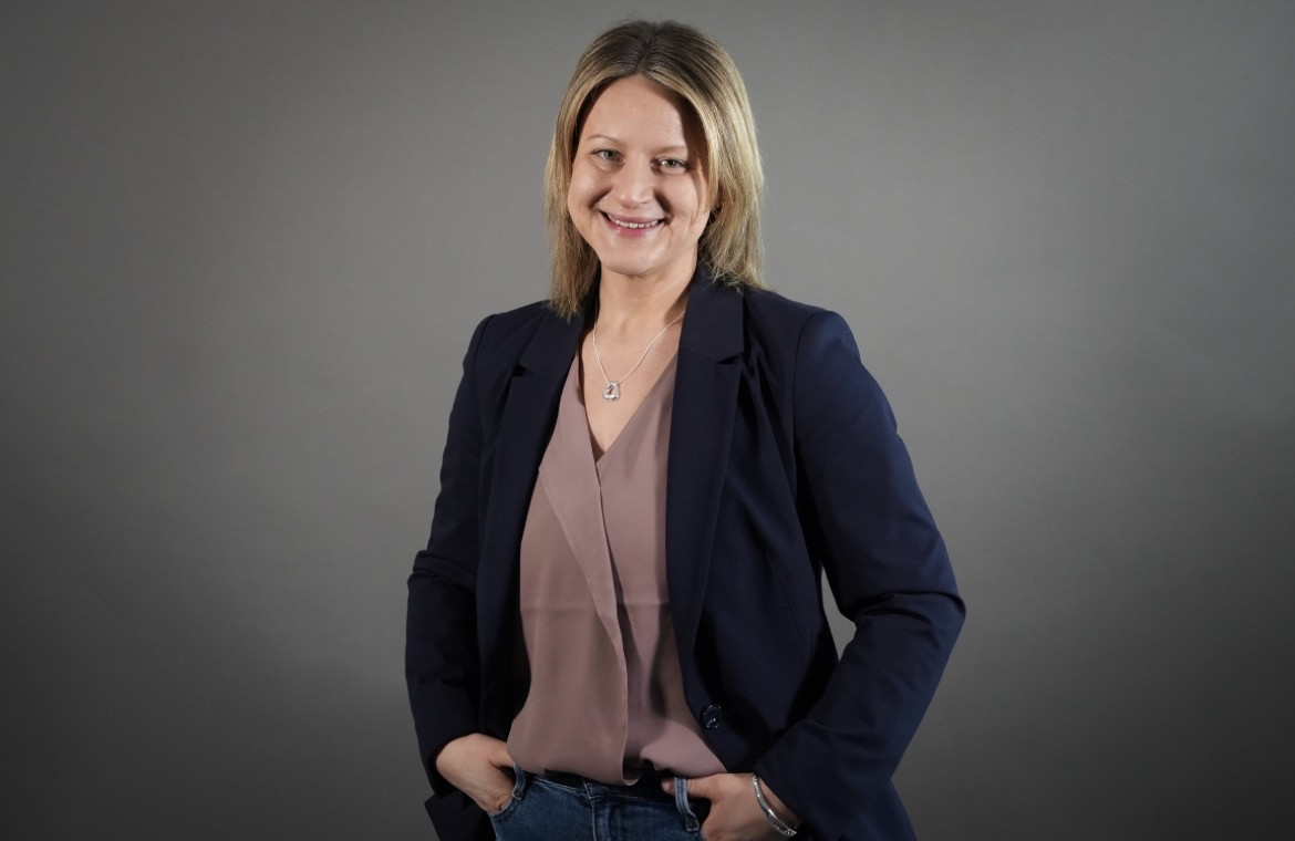 Business-Porträt einer Frau im Blazer vor grauem Hintergrund