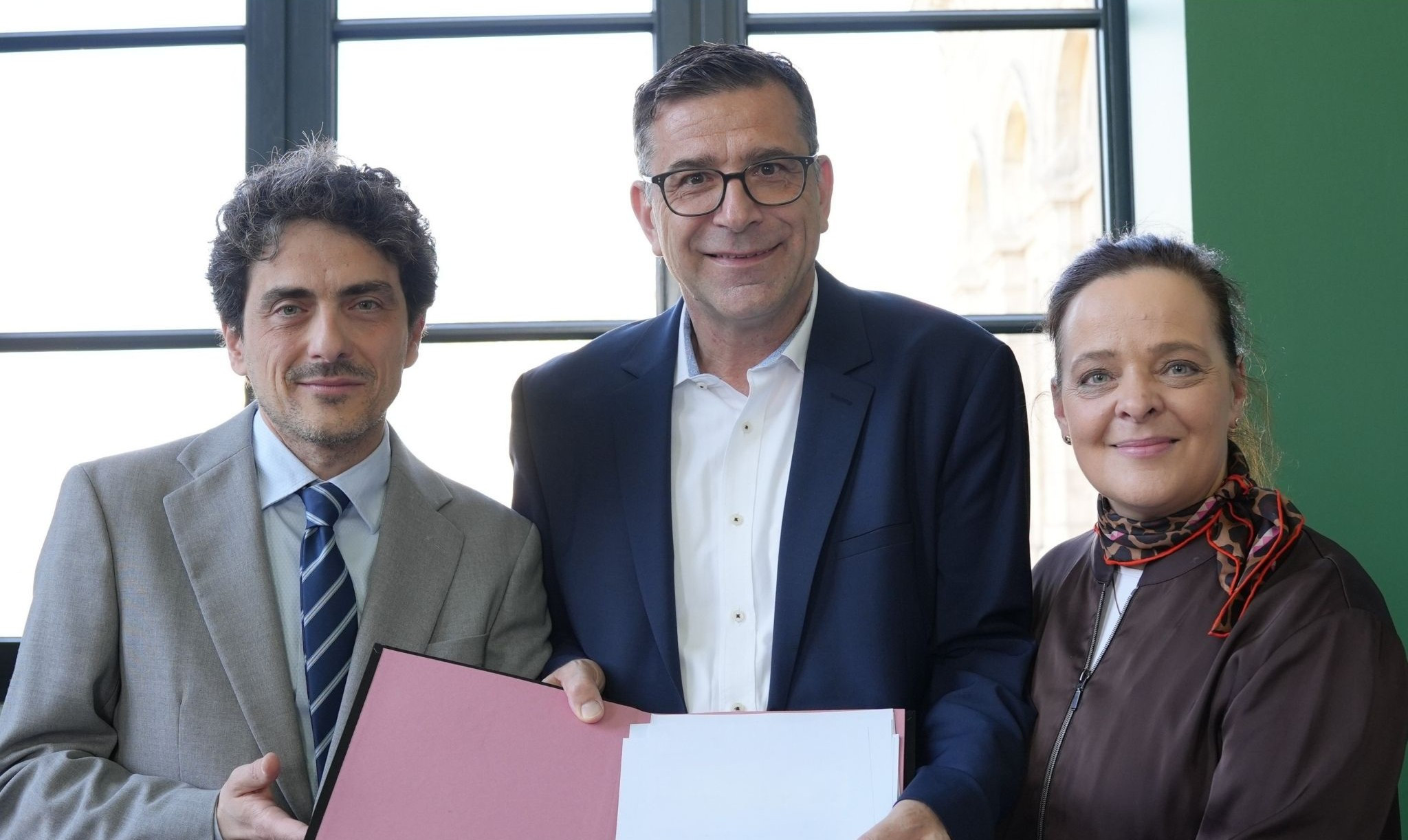 Gruppenfoto mit Musikdirektor bei offizieller Übergabe eines Dokuments