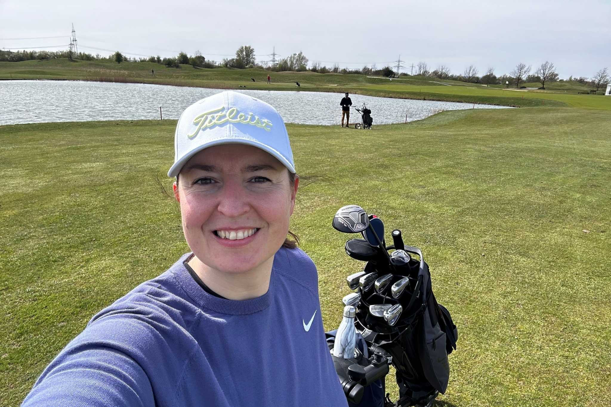 Golfspieler mit Golfausrüstung auf dem Platz, grasgeflüster, See im Hintergrund