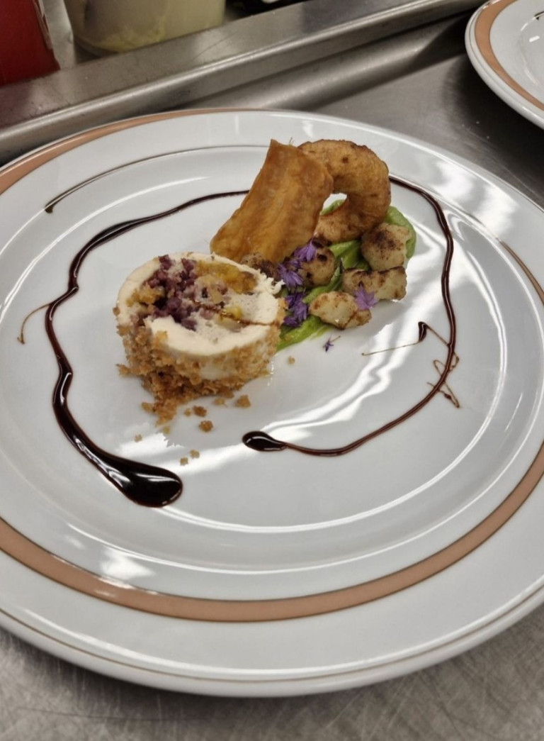 Gourmetgericht auf einem weißen Teller, angerichtet mit Sauce, Gemüse und essbaren Blüten, aus dem Artikel Koch 6