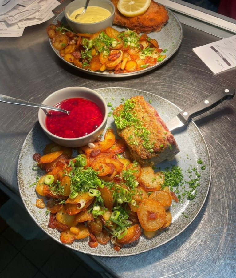 Leckeres Gericht mit Bratkartoffeln, Fleisch und Preiselbeersoße auf einem Teller, angerichtet in einem Restaurant