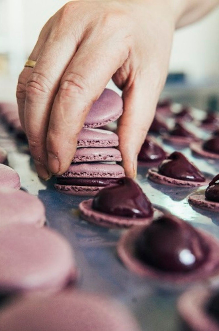 Hand fertigt lila Macarons in der Nobilis Konditorei – Nahaufnahme der Herstellung