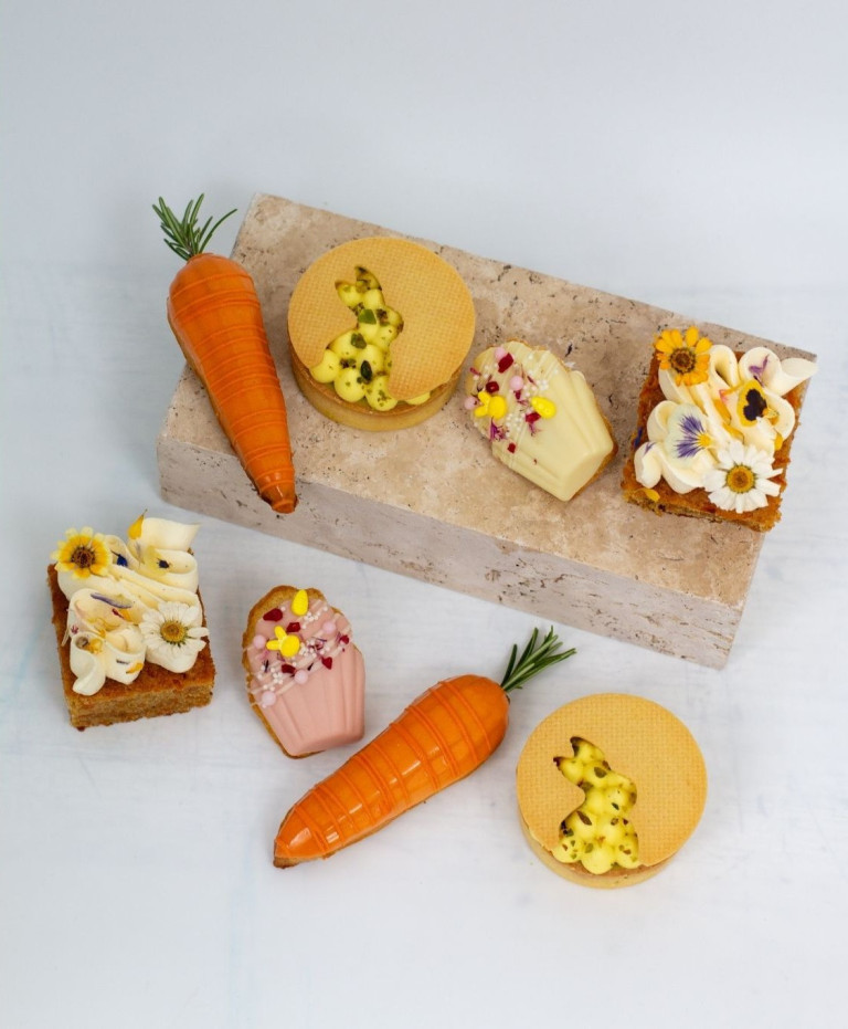 Feine Nobilis Patisserie-Kunstwerke mit Ostermotiven, Karotten und Blumen-Dekor auf hellem Hintergrund